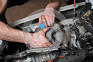 Car mechanic hands opening or closing antifreeze container.