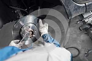 Car mechanic hands replace brakes in garage.