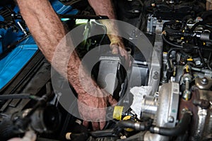 Car mechanic hands replacing intercooler on a car engine.