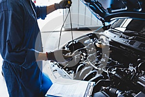 Car mechanic holding checking gear oil to maintenance vehicle by customer claim order in auto repair shop garage. Engine repair