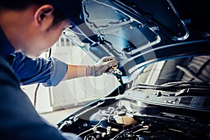 Car mechanic holding checking gear oil to maintenance vehicle by customer claim order in auto repair shop garage. Engine repair