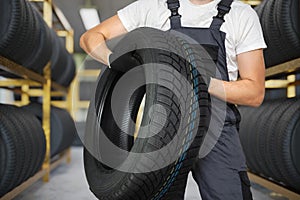 Car mechanic is holding winter tire in hands