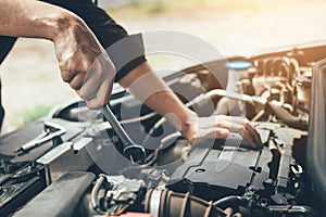 Car mechanic is holding a wrench ready to check the engine and maintenance