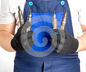 Car mechanic holds fuel car injectors in his hand. The concept of replacing and tuning the fuel system of a car at a car
