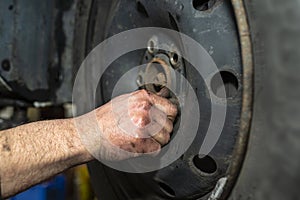 The car mechanic inserts the bolts securing the steel wheel of the car before using the pneumatic wrench.