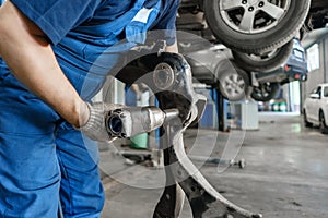 Car mechanic inspecting car wheel and repair suspension detail. Lifted automobile at repair service station. replacement