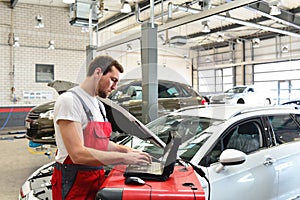 car mechanic inspects vehicle in a workshop - electronic computer check up