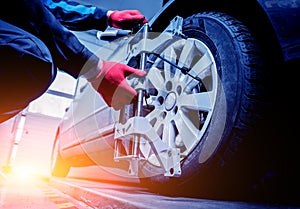 Car mechanic installing sensor during suspension adjustment.