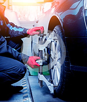 Car mechanic installing sensor during suspension adjustment.