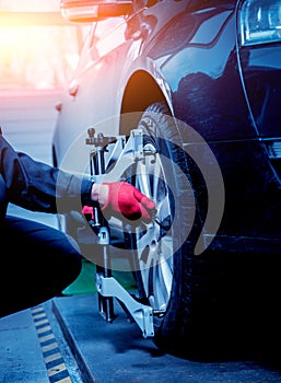 Car mechanic installing sensor during suspension adjustment.