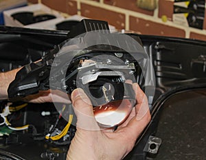 The car mechanic installs the lens in the headlight housing.