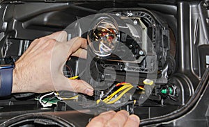 The car mechanic installs the lens in the headlight housing.