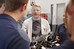 Car mechanic listening to questions from apprentices photo