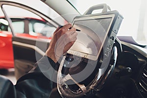 Car mechanic maintains a vehicle with the help of a diagnostic computer - modern technology in the car repair shop