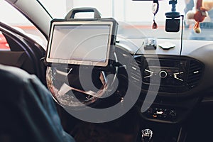 Car mechanic maintains a vehicle with the help of a diagnostic computer - modern technology in the car repair shop