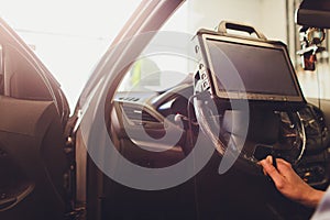 Car mechanic maintains a vehicle with the help of a diagnostic computer - modern technology in the car repair shop