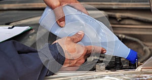 Car Mechanic man hands pouring Deionized purified Distilled water for car battery mechanical service. Close up hands man hold