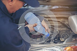 Car Mechanic man hands pouring Deionized purified Distilled water for car battery mechanical service. Close up hands man hold