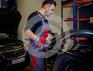 Car mechanic mounts tire on wheel in a workshop