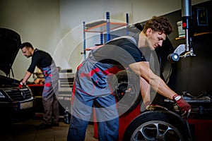 Car mechanic mounts tire on wheel in a workshop