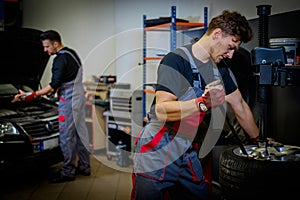 Car mechanic mounts tire on wheel in a workshop