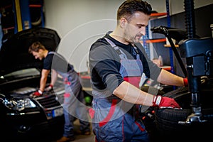 Car mechanic mounts tire on wheel in a workshop