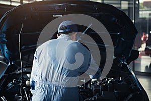 Car mechanic opening car hood for internal checking to maintenance vehicle by customer claim order in auto repair shop garage.