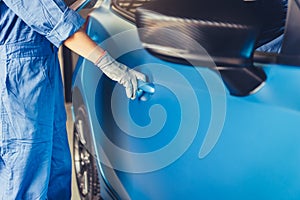 Car mechanic opening side door to maintenance vehicle check for customer claim order in auto repair shop garage. Internal repair