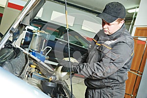 Car mechanic pouring oil into motor engine