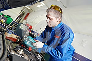 Car mechanic pouring oil into motor engine