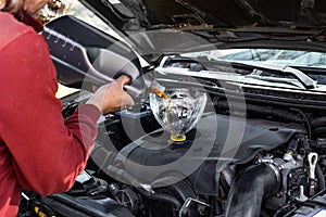 Car mechanic pours engine oil into the car engine through the funnel. Changing the oil in the car