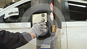 The car mechanic presses a button on the lifting and transport mechanism of the jack to lower the car. Auto repair