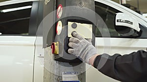 The car mechanic presses a button on the lifting and transport mechanism of the jack to lower the car. Auto repair