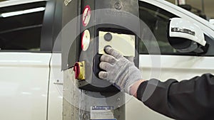 The car mechanic presses a button on the lifting and transport mechanism of the jack to lower the car. Auto repair