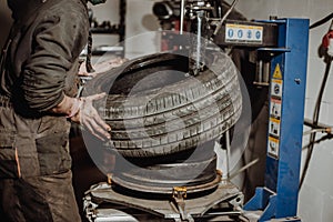 Car mechanic removing tire from rim with tire removal machinery equipment, pneumatic wrench unscrews the wheel