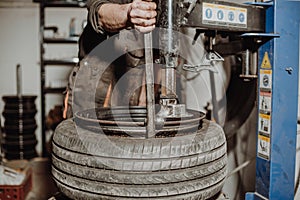 Car mechanic removing tire from rim with tire removal machinery equipment, pneumatic wrench unscrews the wheel