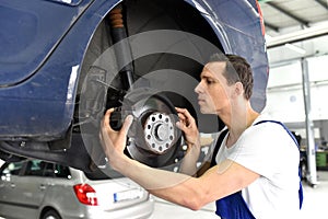 Car mechanic repairs brakes of a vehicle on the lifting platform