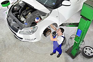 Car mechanic repairs brakes of a vehicle on the lifting platform