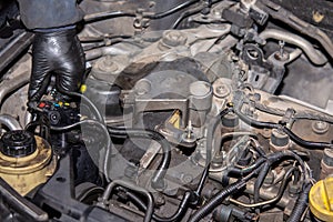 Car mechanic repairs diesel engine. Old and dirty car engine with car mechanics hands. Car repairing concept in the garage