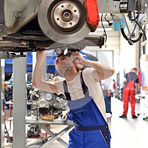 Car mechanic repairs vehicle in a workshop