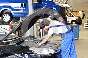 Car mechanic repairs vehicle in a workshop