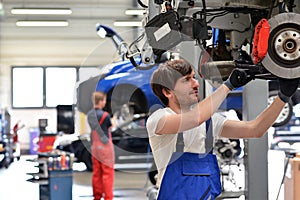 Car mechanic repairs vehicle in a workshop