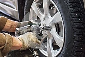 Car mechanic replace car wheels of lifted automobile by pneumatic wrench at repair service shop garage station photo