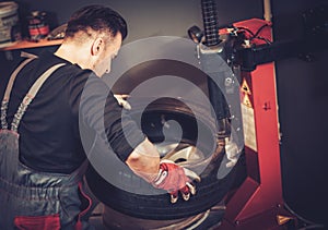 Car mechanic replace tire on wheel in auto repair service. photo