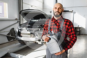 The car mechanic replaces the oil in the car. Car mechanic replacing and pouring fresh oil into engine car