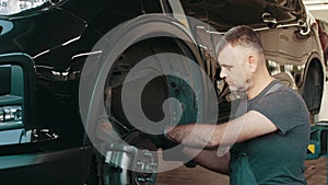 Car mechanic replacing car wheel brake shoes of lifted automobile ac repair service station. Mechanic repairing car at