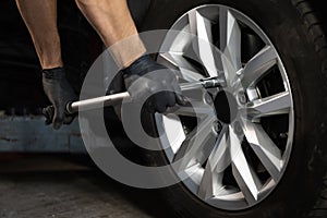 Car mechanic replacing a car wheel tire in garage workshop. Auto service. Repairman mounting wheel tire at service