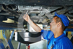 Car mechanic replacing oil from motor engine photo