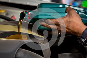 Car mechanic replacing and pouring fresh oil into engine at maintenance repair service station, Mechanic pouring oil into car at t