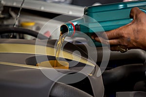 Car mechanic replacing and pouring fresh oil into engine at maintenance repair service station, Mechanic pouring oil into car at t